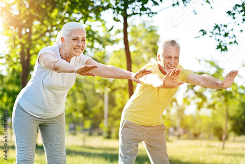 Joyful senior couple doing sport exercises together
