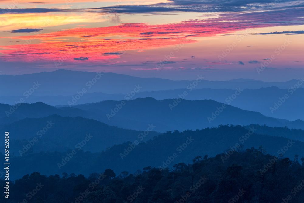 Layer of mountains in the mist at sunset time with burning sky, Nan Province, Thailand