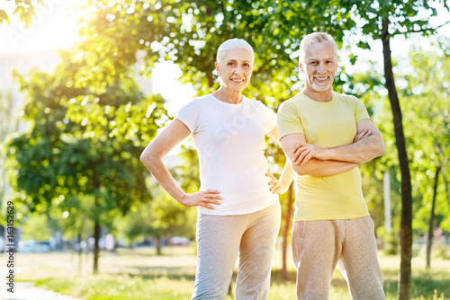 Positive retired couple standing in the park