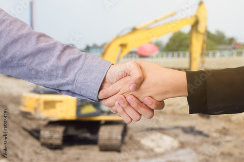 Architects shaking hands at construction site against
