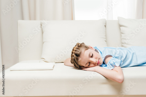 adorable preteen girl sleeping on sofa with white book
