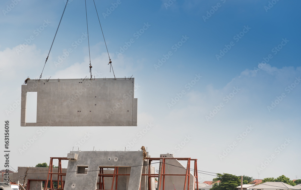 Construction site crane is lifting a precast concrete wall panel. Stock