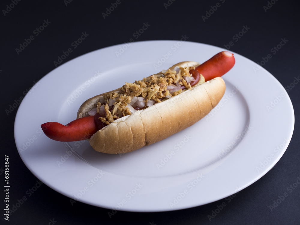 Henstilling Clancy del Danish hot dog with red sausage, ketchup, mustard sauce and raw and fried  onions on white plate, isolated on black background Stock Photo | Adobe  Stock