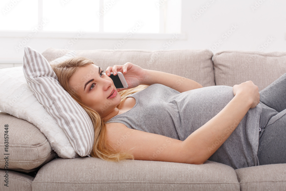 Smiling pregnant woman talking on her smartphone Smiling pregnant woman talking on her smartphone