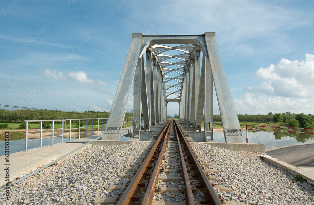 The railway bridge through the river on blue sky background. The railway bridge through the river on blue sky background.