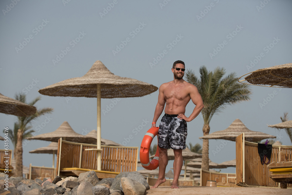 Man with muscular body posing with red life ring