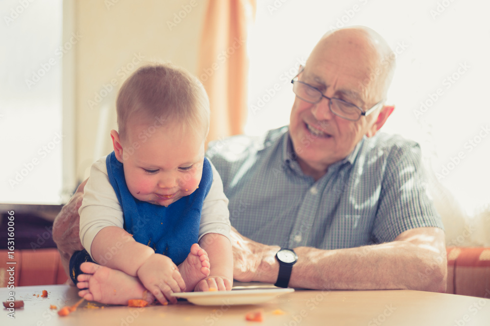 Grandfather helping baby learning to eat solids Grandfather helping baby learning to eat solids