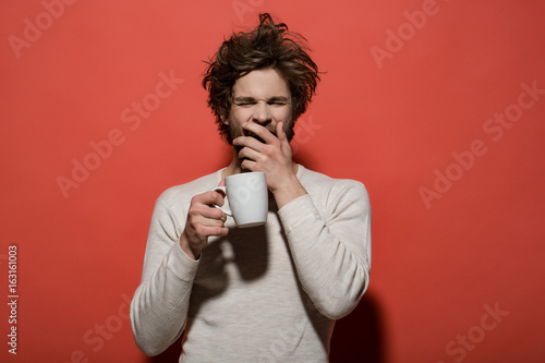 Photography sleepy yawning man with cup of tea or coffee