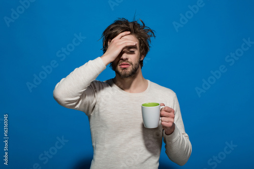 sleepy tired man with headache hold cup of tea