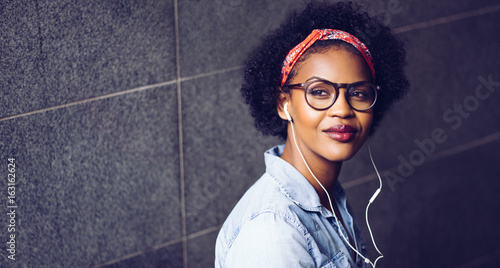 Stylish young woman listening to music on earphones photo