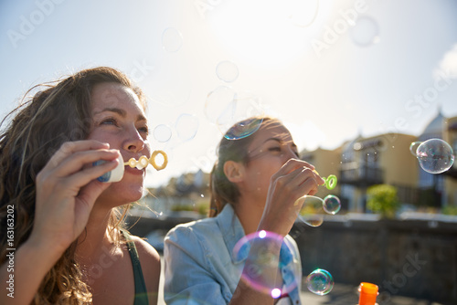 Two charming young ladies blowing bubbles