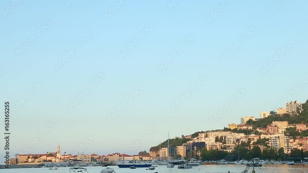 Seashore morning panorama of city on mountains. Sunny morning. Boats and yachts sway on the sea waves. Buildings right on the rock stones. Sea bay. Sea coast line sunny morning.