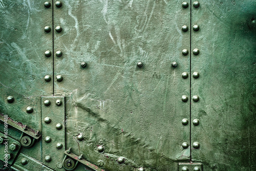 Abstract green industrial metal background texture with bolts and rivets. Old painted metal background, detail of military aircraft, surface corrosion, metal texture with rivets