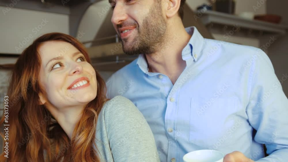Side view of happy caucasian couple of young woman and her husband in kitcen drinking coffee. Indoor. Side view of happy caucasian couple of young woman and her husband in kitcen drinking coffee. Indoor.