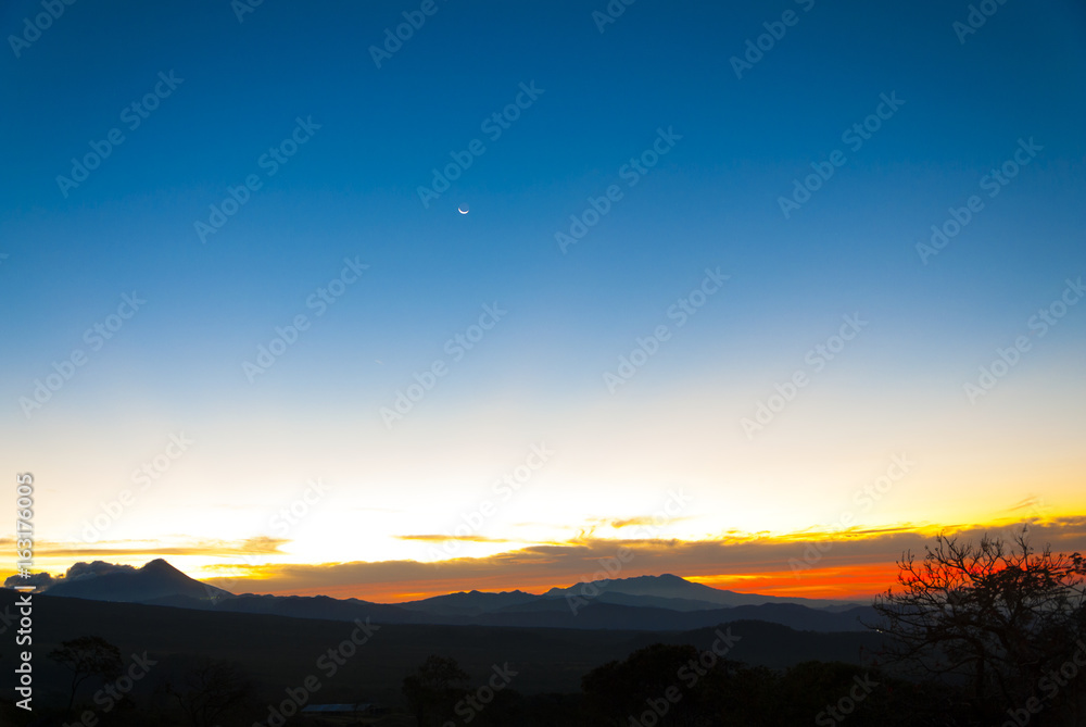 Sunrise clouds and mountains in Guatemala, dramatic sky with striking colors and moon. La Reunion. Sunrise clouds and mountains in Guatemala, dramatic sky with striking colors and moon. La Reunion.