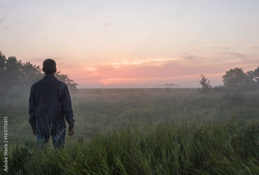 A man stands at dawn in the fog A man stands at dawn in the fog