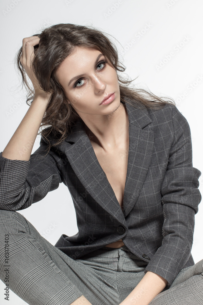 Awesome Caucasian attractive shy sexy female model with brunette hair sitting in studio, wearing formal suit, isolated on white background Awesome Caucasian attractive shy sexy female model with brunette hair sitting in studio, wearing formal suit, isolated on white background