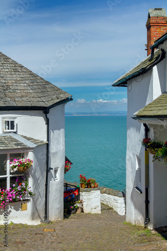 A narrow picturesque street in the small and beautiful village of Clovelly. Between the white houses you can see the sea and the distant shore of Wales. Devon. England photo