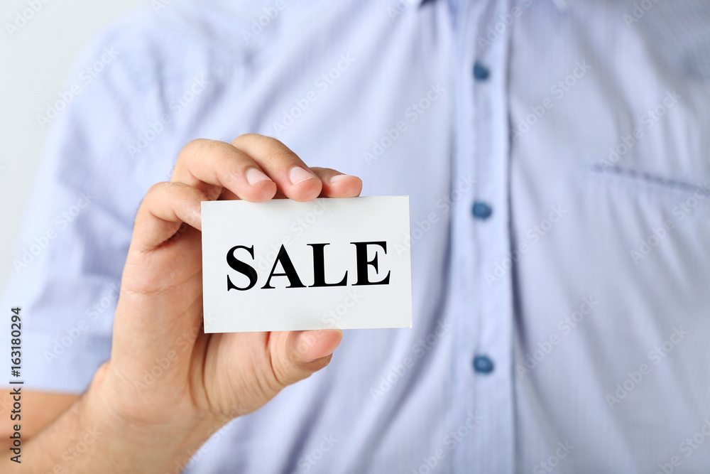 Male hand holding a business card with word Sale Male hand holding a business card with word Sale