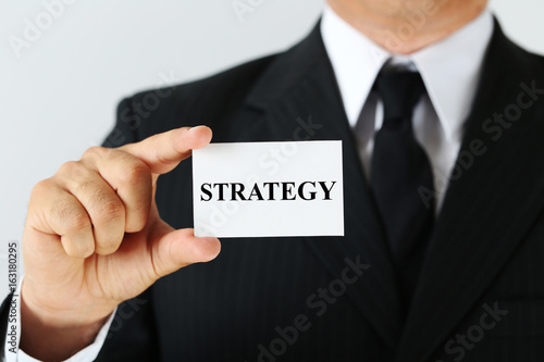 Businessman holding card with word Strategy