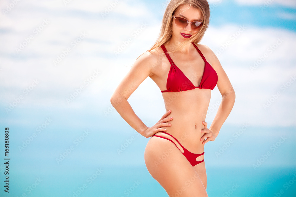 Woman in swim posing on beach over sea background at summer.