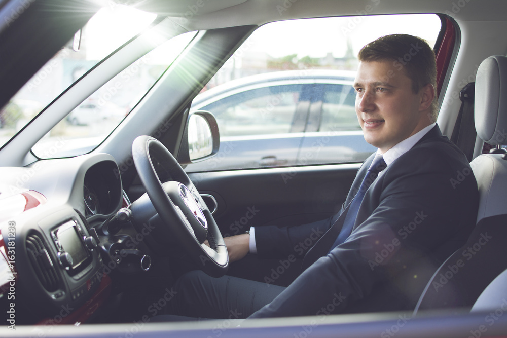 Businessman sitting in his car in a highway jam. Looking in the distance while in traffic. Suit and tie businessman sitting in his automobile. Businessman sitting in his car in a highway jam. Looking in the distance while in traffic. Suit and tie businessman sitting in his automobile.