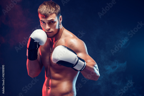 Aggressive shirtless boxer on dark smoke background. photo