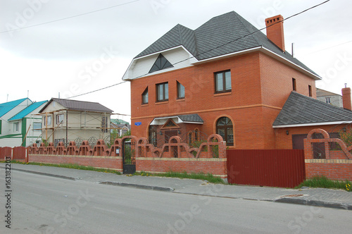 Fototapeta Naklejka Na Ścianę i Meble -  Современный коттедж на фоне многоэтажной застройки на заднем плане

