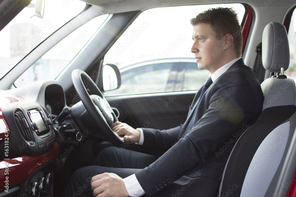 Businessman sitting in his car in a highway jam. Looking in the distance while in traffic. Suit and tie businessman sitting in his automobile. Businessman sitting in his car in a highway jam. Looking in the distance while in traffic. Suit and tie businessman sitting in his automobile.