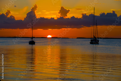 sunset over ocean bay with anchored boats © kevin