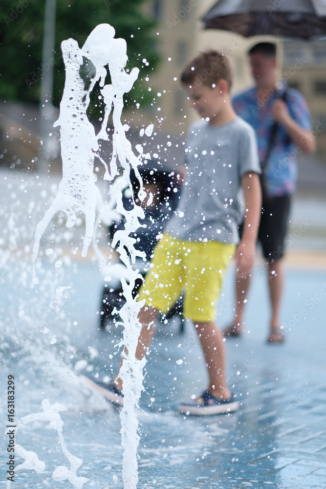 Obraz premium Children play with water in a fountain on a hot day
