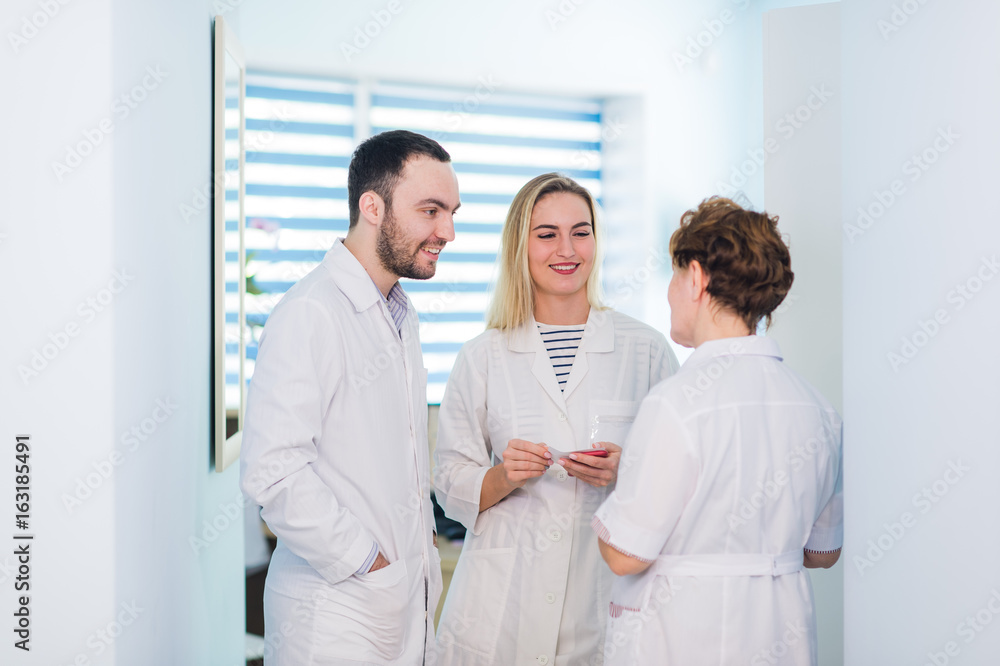 Mature doctor discussing with nurses in a hallway hospital. Doctor discussing patient case status with his medical staff after operation. Mature doctor discussing with nurses in a hallway hospital. Doctor discussing patient case status with his medical staff after operation.