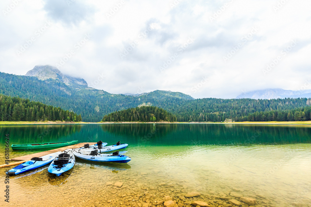 Kayaks docked on the shore of Black Lake. Mountain landscape at cloudy daytime, Durmitor National Park, Zabljak, Montenegro. Summer recreations, travel and vacation.