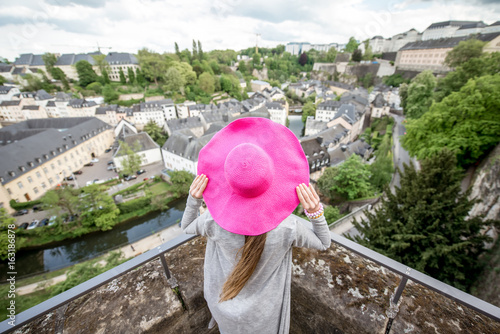 Female traveler standing back with pink hat and enjoy beautiful cityscape view on the old town in Luxembourg city photo