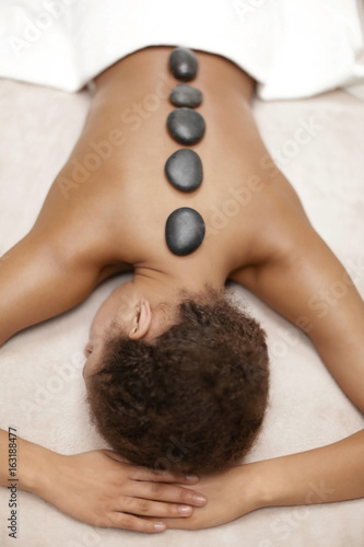 African-American woman with stones on back in spa salon