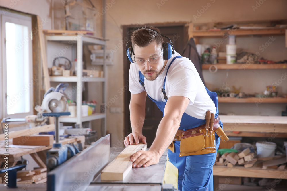 Focused carpenter checking timber on table saw Focused carpenter checking timber on table saw