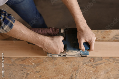 Carpenter working with grinder in shop