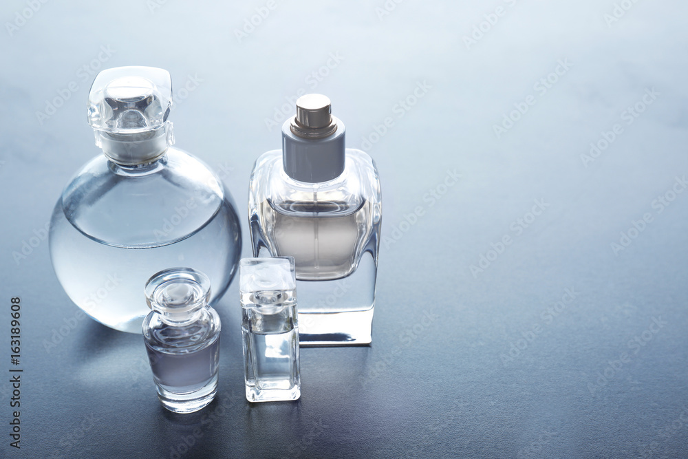 Different perfume bottles on grey background - obrazy, fototapety, plakaty 