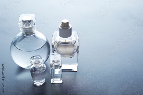 Different perfume bottles on grey background