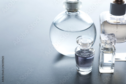 Different perfume bottles on grey background
