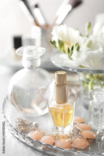 Glass tray with perfume bottles on grey table