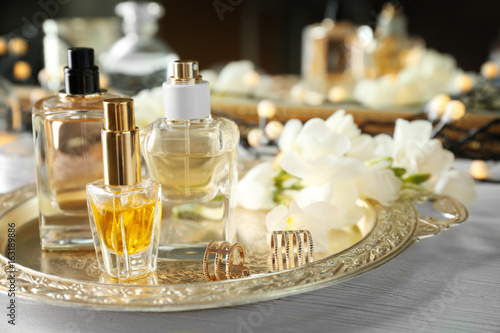 Golden tray with perfume bottles on white table