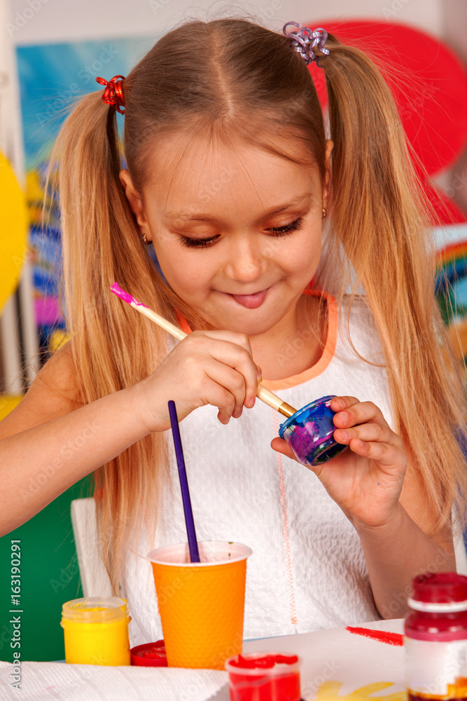 Little student painting in art school class. Child drawing by paints on