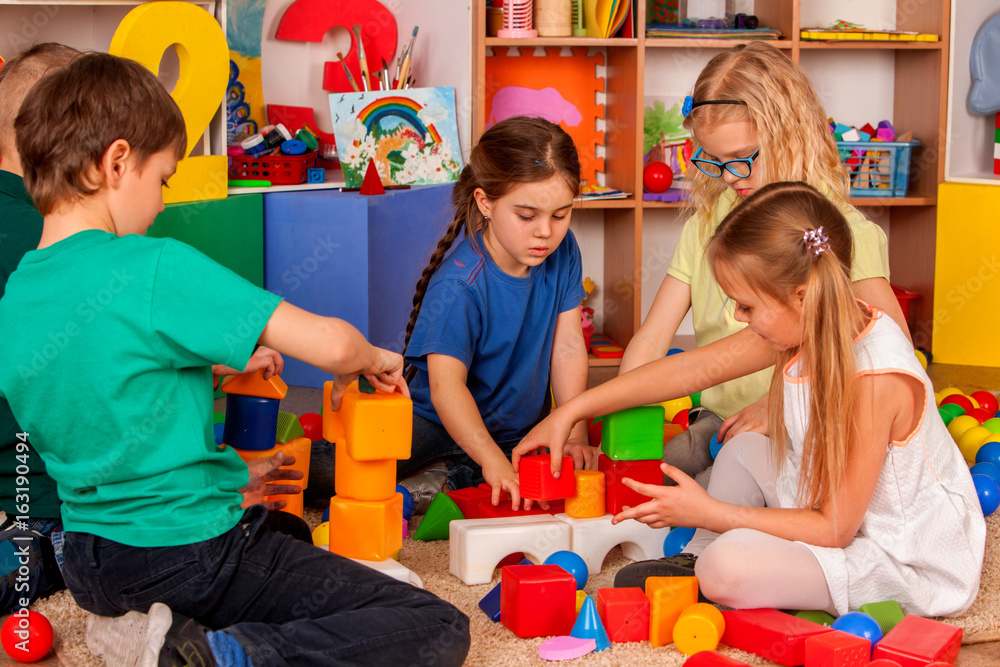 Children building blocks in kindergarten. Group kids playing toy