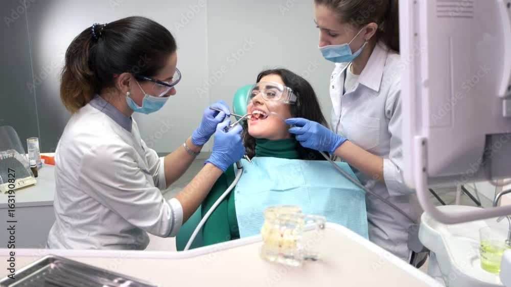 Two stomatologists busy with patient. Lady in dental safety glasses. Two stomatologists busy with patient. Lady in dental safety glasses.
