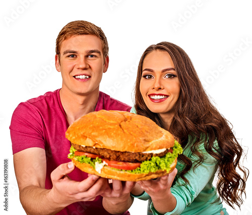 Couple eating fast food. Man and woman treat big hamburger with ham. Friends give burder junk on white background isolated. Harm from fast food idea.