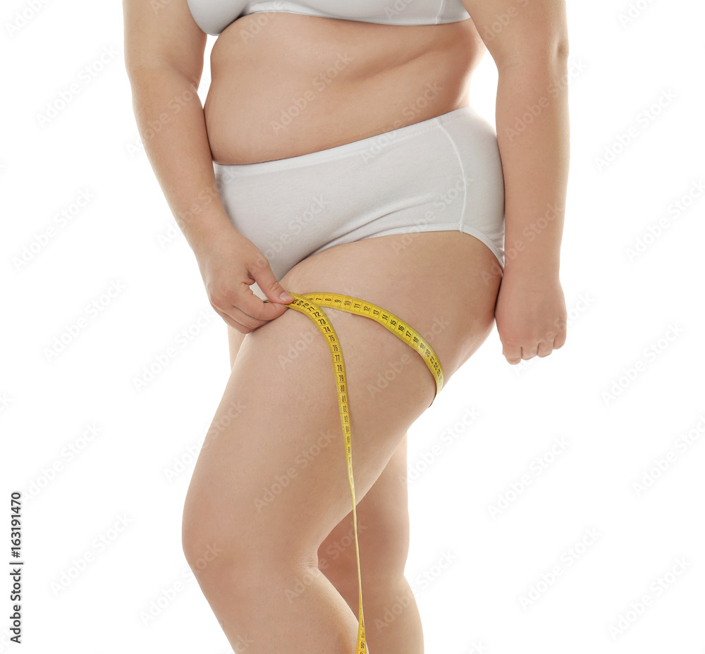 Overweight woman in underwear measuring her thigh on white background. Diet concept