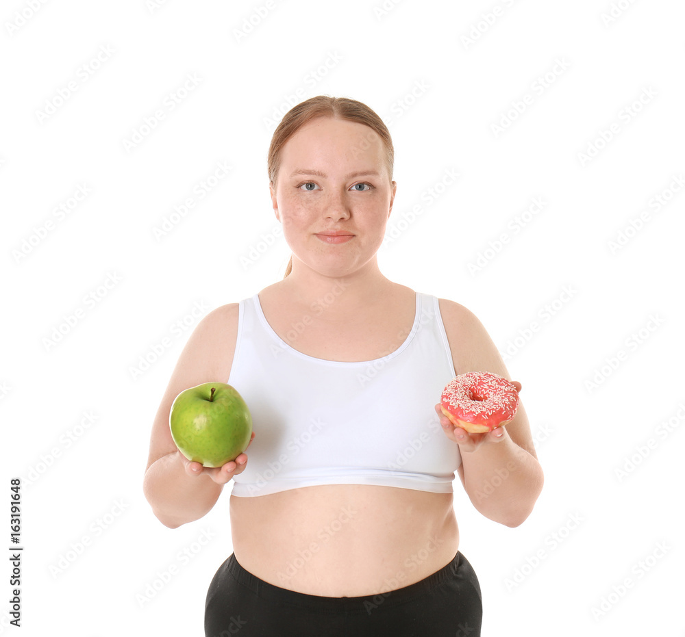 Overweight young woman with apple and donut on white background. Diet concept Overweight young woman with apple and donut on white background. Diet concept