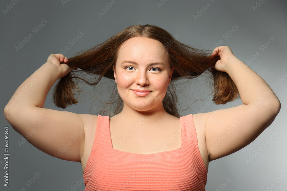 Fototapeta premium Overweight young woman on gray background. Diet concept