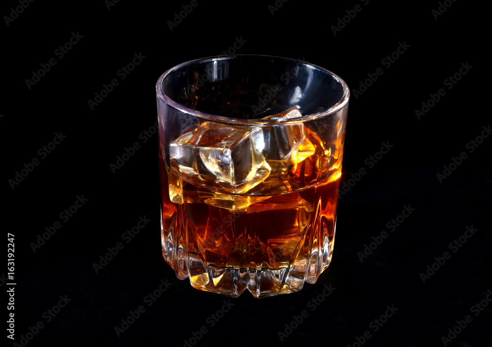 Glass of whiskey or bourbon with ice on black stone table. Glass of whiskey or bourbon with ice on black stone table.